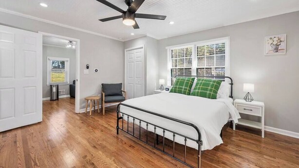 A bedroom with a bed, a ceiling fan, a window with blinds, a nightstand, and a chair. - Private 1BR Cottage In Downtown Historic Norcross (Norcross)