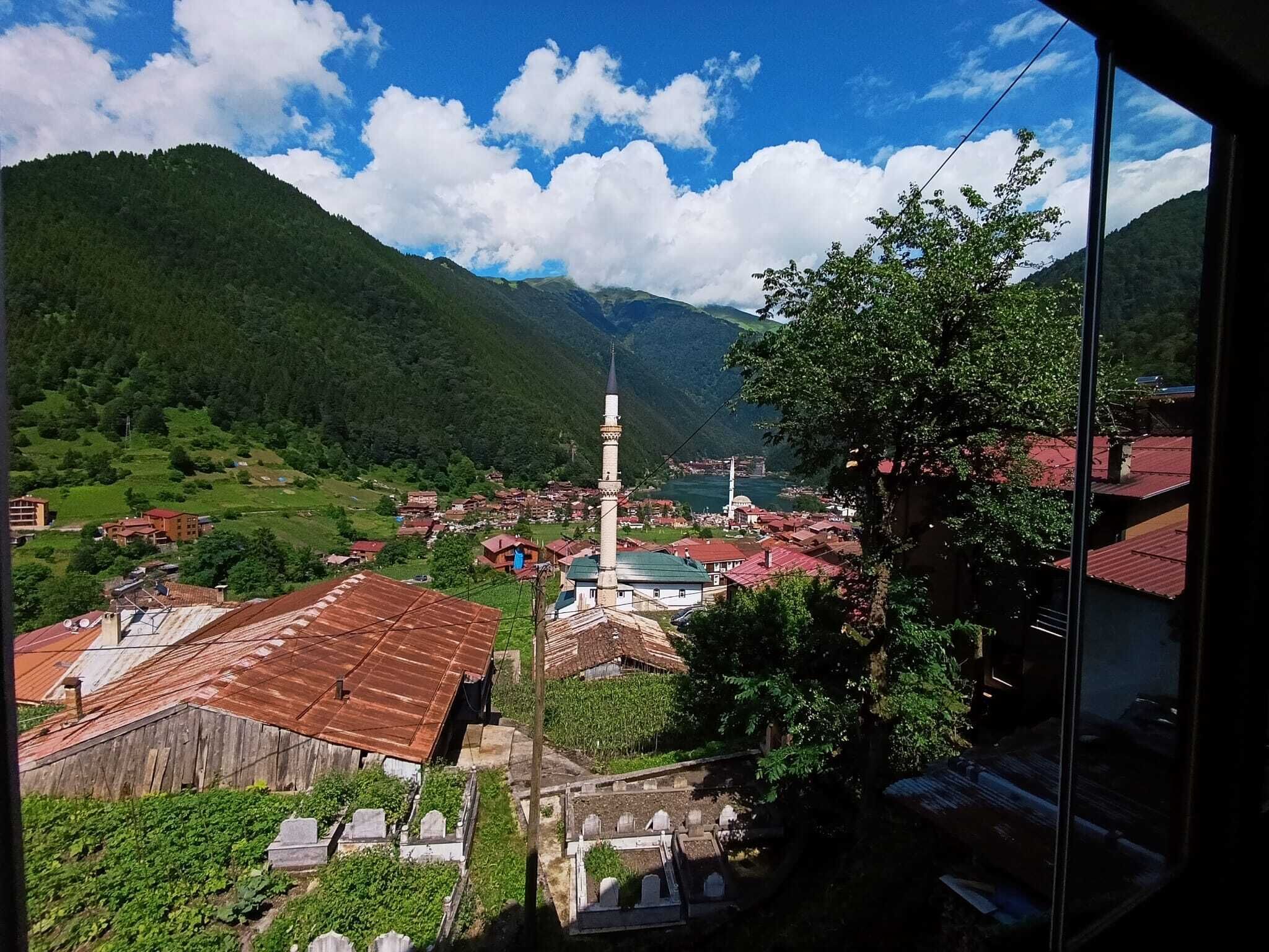Un pueblo con una iglesia destacada, rodeado de montañas y vegetación.