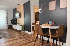 A modern dining area with a round table, two brown chairs, a white console, and a grey accent wall.