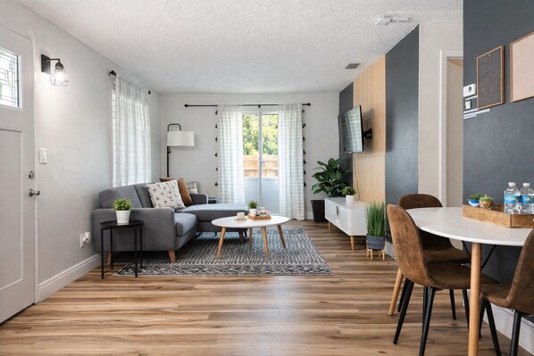 Ein modernes Wohnzimmer mit Sofa, Couchtisch und Essbereich.