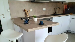 A modern kitchen with a central island, two white bar stools, a sink, and a stove. - "Little time out" - fantastic view of the Franconian countryside - ideal for bikers. (Scheßlitz)