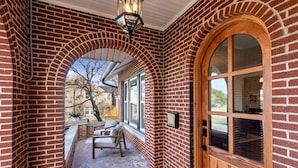 Fachada de ladrillo con puerta de madera y ventanas en arco.