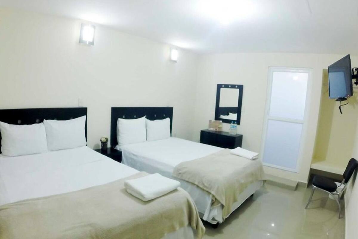 A hotel room with two beds, a TV, a desk, and a chair.