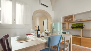 A dining area with a table set for two, a wine bottle, glasses, and a small plant on a shelf. - 2018 Mimì Maison by Barbarhouse (Lecce)