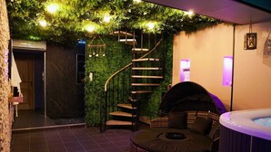 A modern indoor space with a spiral staircase, a hot tub, and a seating area.
