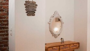 A bathroom with a wooden vanity, a mirror, and a wall-mounted sign with text.
