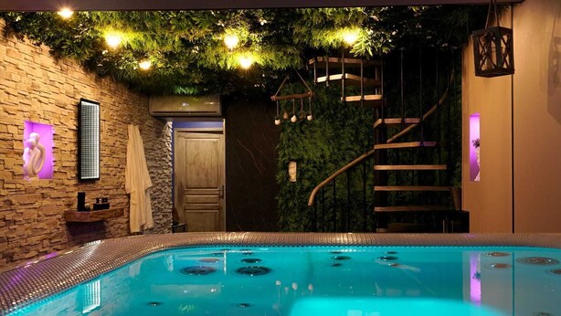 A modern indoor pool with a stone wall and a wooden door.