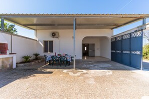 A covered patio area with a table and chairs, a small garden, and a blue gate. - 2438 Villino Sunny by Barbarhouse (Lecce)