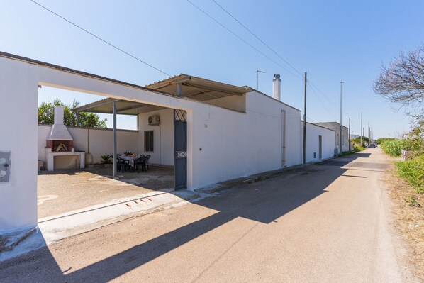 A narrow street with a white building featuring a covered outdoor seating area and a chimney. - 2438 Villino Sunny by Barbarhouse (Lecce)