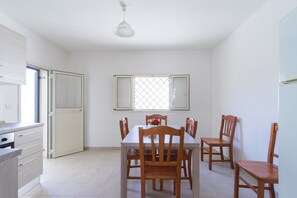 A dining area with a table and chairs, a window with a grid pattern, and a door leading to another room. - 2438 Villino Sunny by Barbarhouse (Lecce)