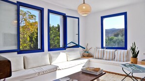 Una sala de estar moderna con un sofá, una mesa de centro y ventanas grandes con marcos azules.