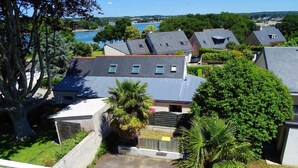 Een woonwijk met huizen, een grote boom en een waterpartij op de achtergrond.