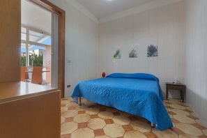 Un dormitorio con una cama, una mesita y una silla.