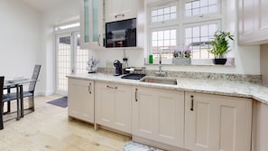 A modern kitchen with a large window, a Bosch microwave, and a sink. - Charming 5-bed House in Romford (Romford)