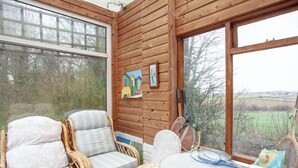 A cozy room with wicker furniture, a glass table, and a view of the countryside. - 2 bedroom accommodation in Clyst Honiton, near Exeter (Clyst Honiton, near Exeter)