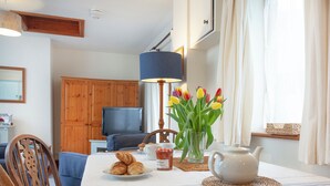 A dining area with a table set for breakfast, including croissants, a teapot, and a vase with tulips. - 2 bedroom accommodation in Clyst Honiton, near Exeter (Clyst Honiton, near Exeter)