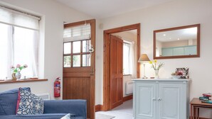 A room with a blue sofa, a light blue cabinet, and a mirror on the wall. - 2 bedroom accommodation in Clyst Honiton, near Exeter (Clyst Honiton, near Exeter)