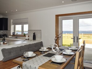 A modern kitchen with a large island, a dining area with a view of the sea, and a cozy seating area.