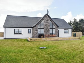 A modern house with a stone facade, large windows, and a sloped roof.