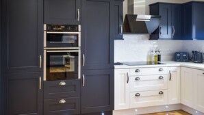 A modern kitchen with dark blue cabinets, stainless steel appliances, and a white countertop. - Uninterrupted views over Coll Beach and sea views out over Broadbay. (All Outer Hebrides)