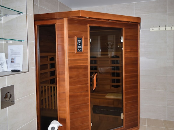 Un ascensor de madera con pantalla digital, barandilla y puerta de cristal.