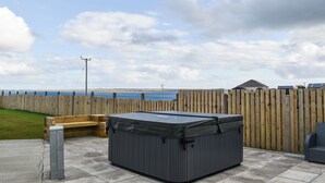 A hot tub in a backyard with a wooden fence, a bench, and a view of the sea. - Uninterrupted views over Coll Beach and sea views out over Broadbay. (All Outer Hebrides)