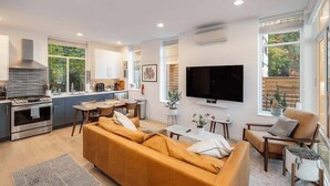 A modern living room with a sofa, TV, and kitchen area.