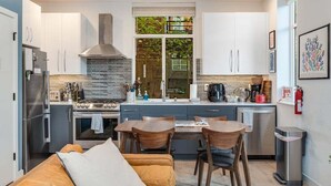A compact kitchen with white cabinets, a stainless steel range, and a large window.
