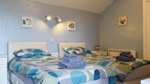 A bedroom with two beds, a wall-mounted light fixture, and a radiator.