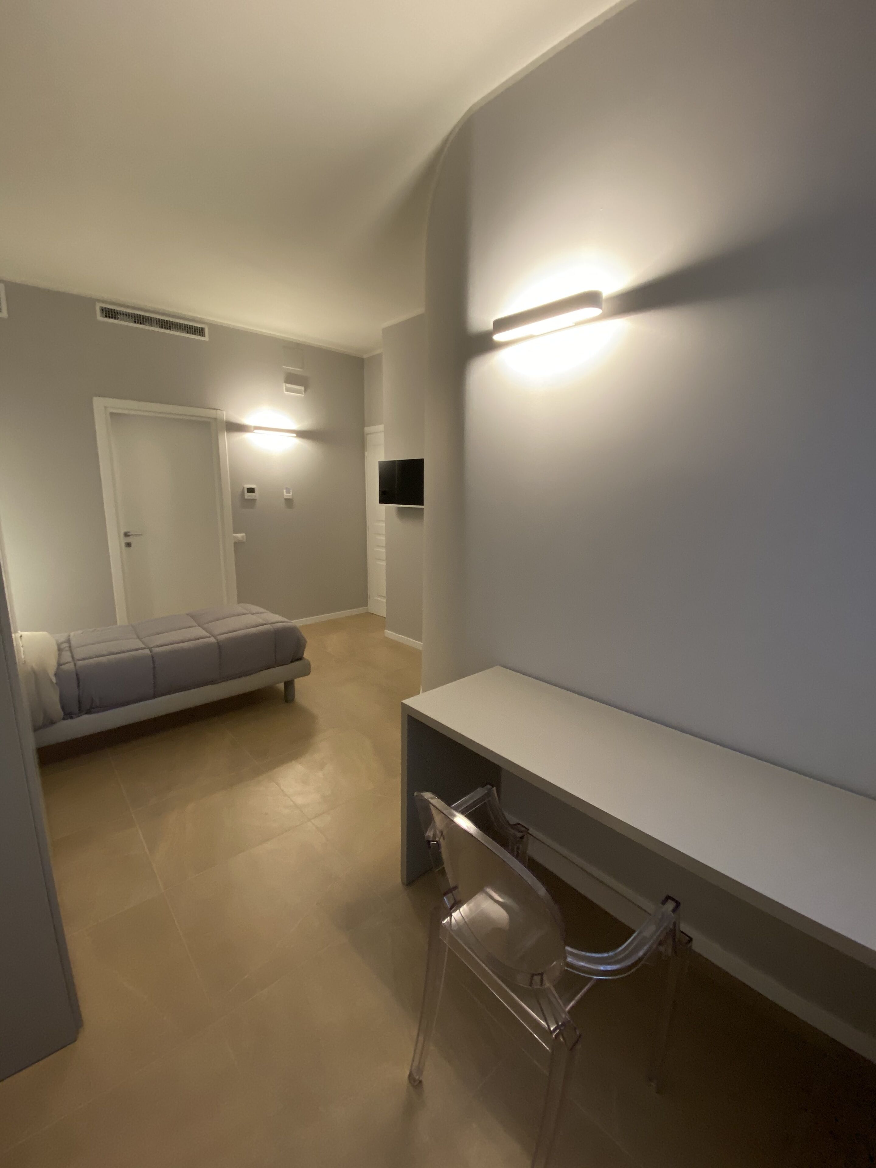 A modern, well-lit room with a bed, a desk, and a chair.