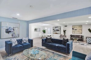 A spacious living area with two sofas, a glass coffee table, and artwork on the walls.