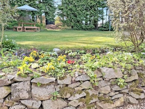 A stone wall with plants, a grassy lawn, and a picnic table in a garden setting. - 2 bedroom accommodation in Alford (Alford)