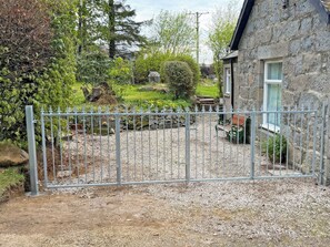 A stone building with a gravel driveway and a metal gate. - 2 bedroom accommodation in Alford (Alford)