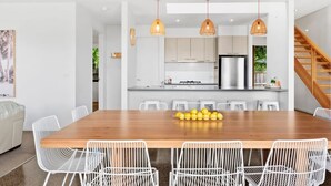 Een moderne keuken met witte kastjes, een houten eettafel en witte stoelen.