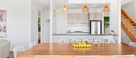 Una cocina moderna con armarios blancos, una mesa de comedor de madera y sillas blancas.