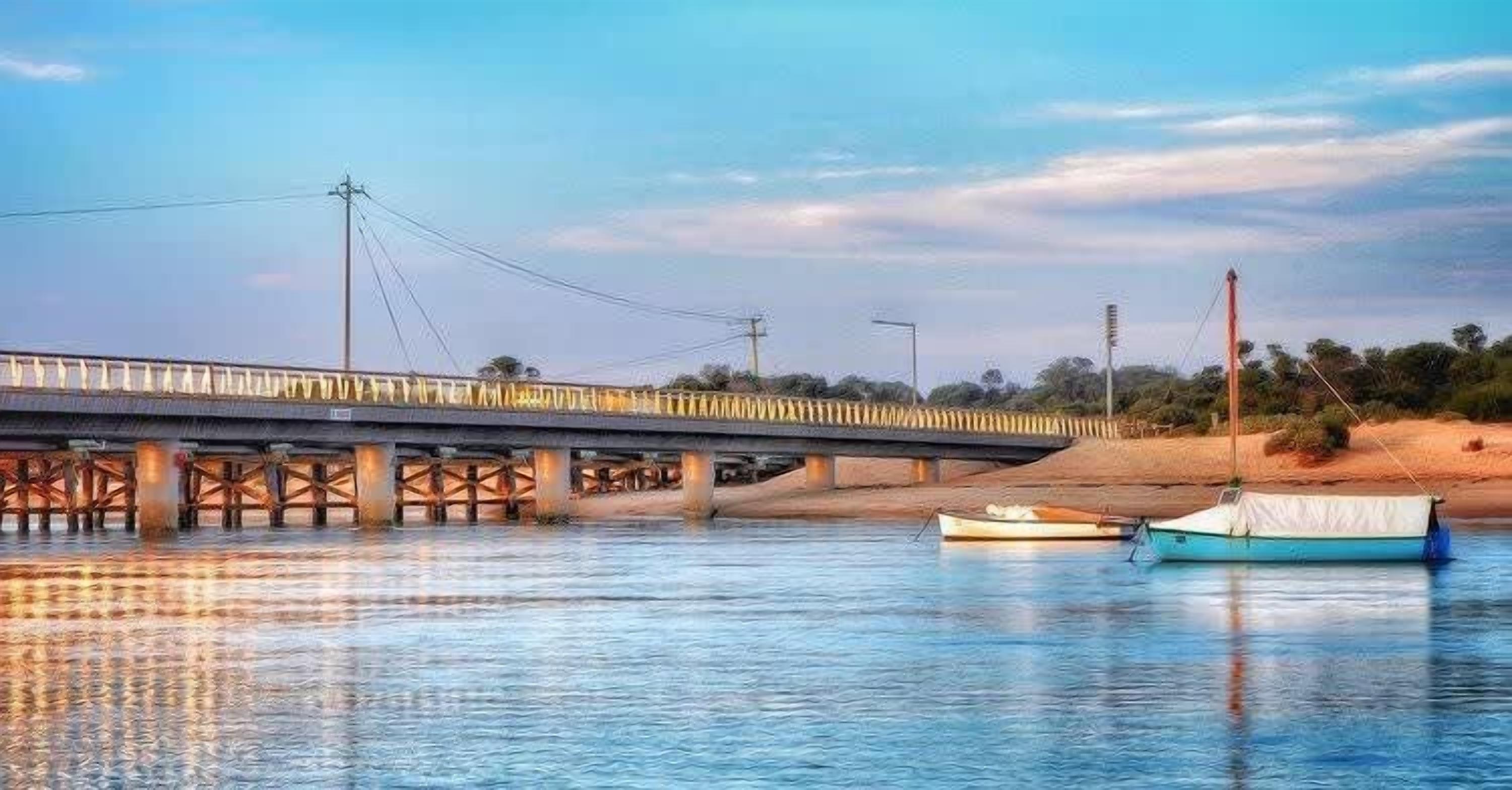 A bridge over a river with boats docked nearby.
