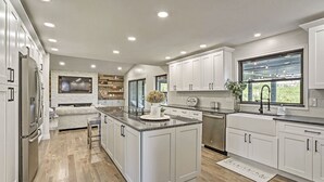 A modern kitchen with white cabinetry, a central island, and a built-in oven. - Broadmoor Luxury Retreat - Mountain View & Hot Tub (Colorado Springs)