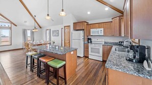 Una cocina amplia con armarios de madera, encimera de granito y una isla central con taburetes.