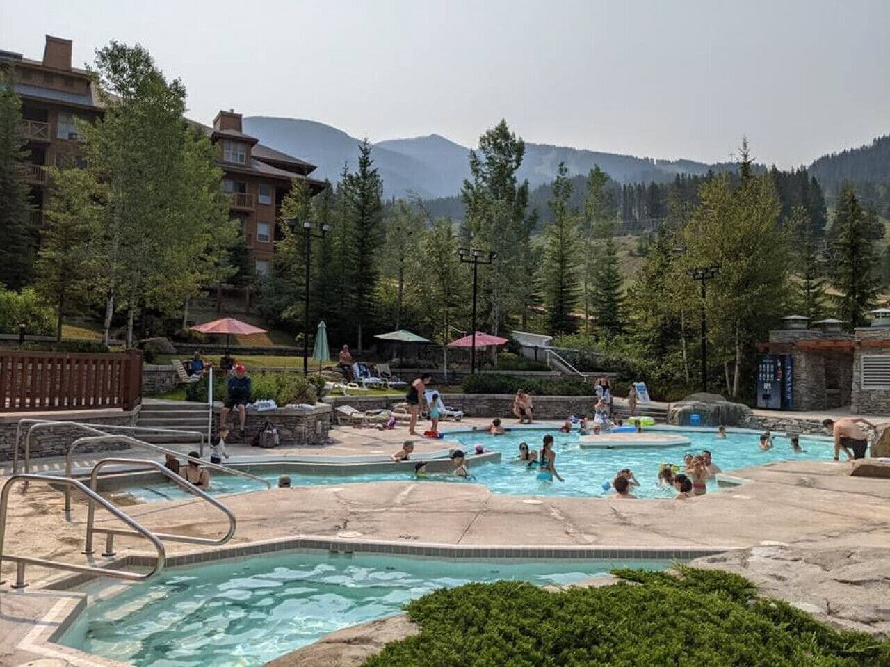 A pool area with multiple swimming pools, surrounded by trees and buildings.