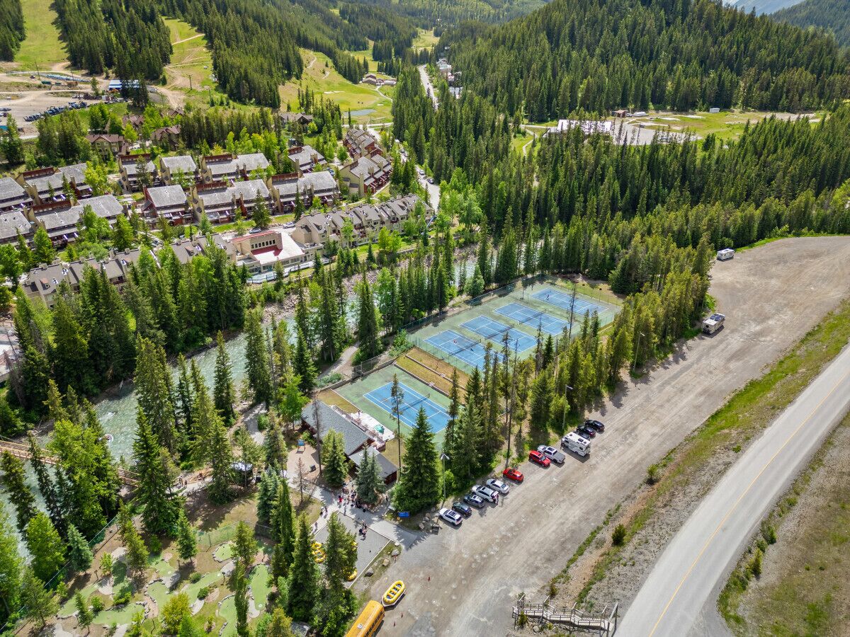 An aerial view of a resort with multiple buildings, a tennis court, and a parking area.