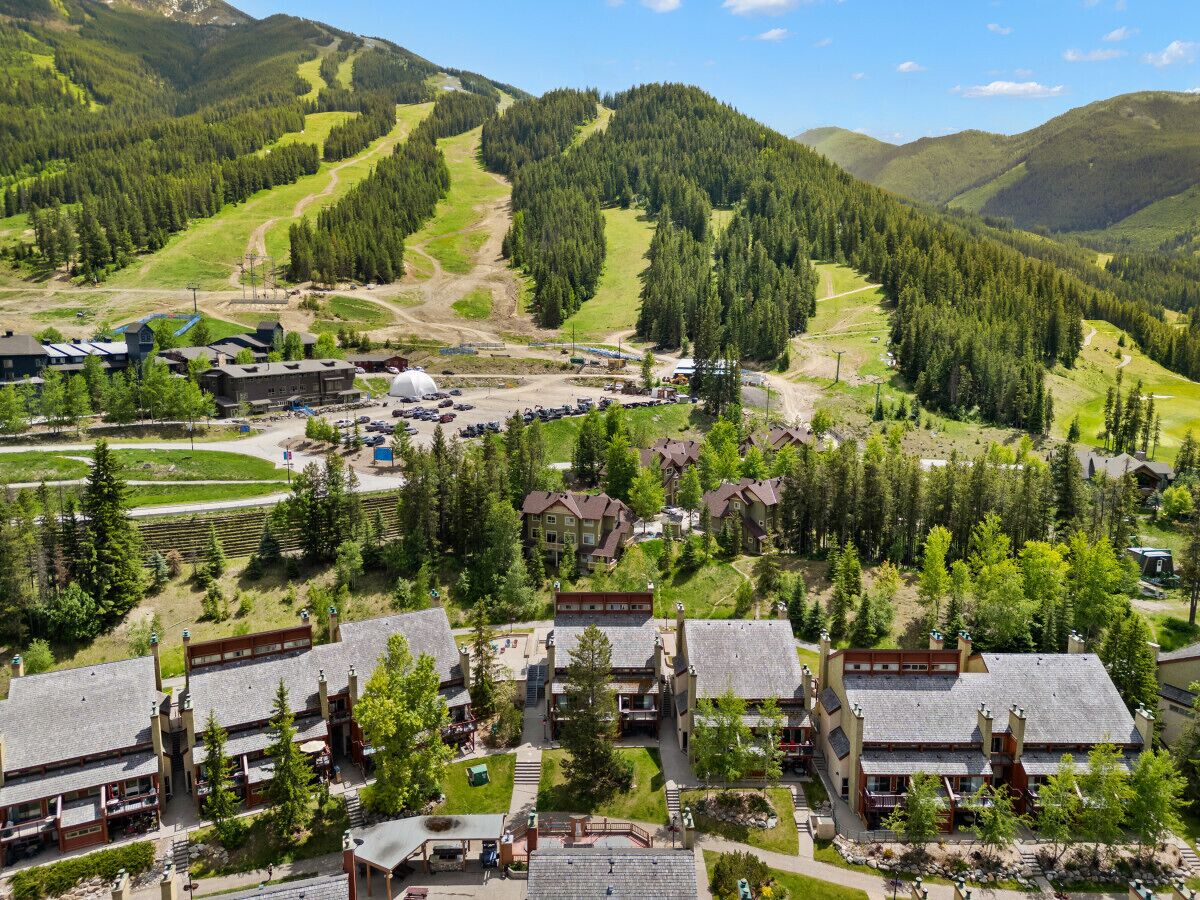A resort with multiple chalet-style buildings, a ski slope in the background, and a well-maintained landscape.