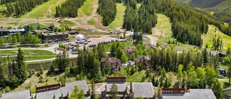A resort with multiple chalet-style buildings, a ski slope in the background, and a well-maintained landscape.