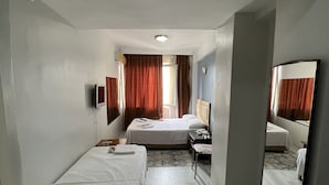 Habitación de hotel con dos camas individuales, un escritorio, una silla, un espejo y una ventana con cortinas.
