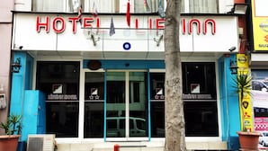 Entrada de un hotel con una puerta azul, un cartel que dice "HOTEL LIFENN HOTEL" y un coche Nissan estacionado afuera.