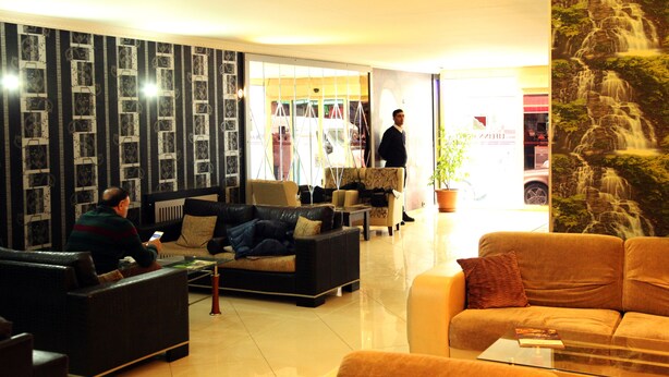 Un hall de hotel con una zona de estar, una escalera y un mural grande.