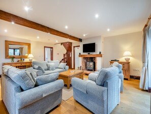 A living room with a fireplace, two sofas, a coffee table, and a TV mounted above the fireplace.