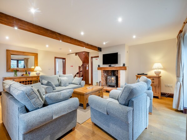 A living room with a fireplace, two sofas, a coffee table, and a TV mounted above the fireplace.