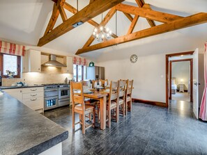 Una cocina amplia con vigas de madera, un comedor con sillas de madera y una isla grande con fregadero.