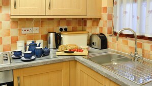 Una cocina con armarios de madera, un tostador, una tetera y un lavamanos.