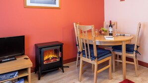 Una habitación acogedora con una mesa de madera, sillas, un televisor y una estufa de leña.
